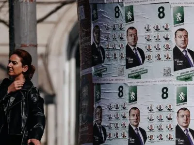 Женщина в Софии идет мимо расклеенных предвыборных плакатов в апреле 2026 года