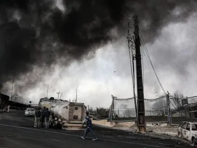 Обугленные машины и клубы дыма рядом с разбомбленным НПЗ "Шахран" в Тегеране