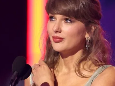 Taylor Swift looks away from camera while speaking into a microphone onstage at the iHeartRadio music awards in LA in March.