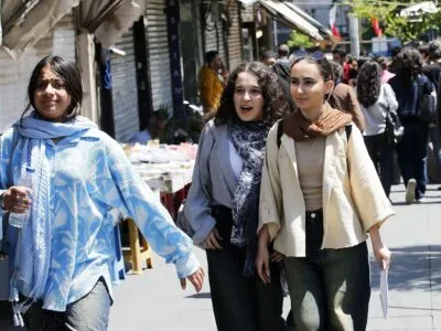 Молодые женщины идут по оживленной торговой улице в Тегеране