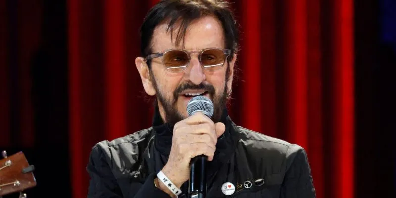 Ringo Starr performs at The Grand Ole Opry on 21 February 2025 in Nashville, Tennessee. He is wearing a black jacket and sunglasses.