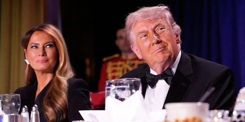 Donald Trump looks to right of frame while slightly smiling along with Melania in the background as they sit at their table during the correspondent's dinner.