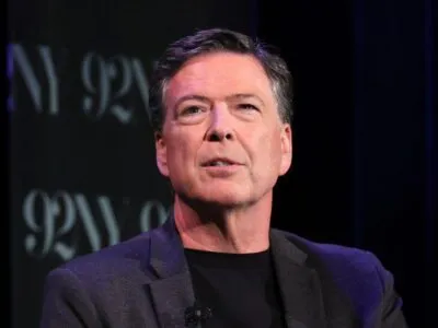 Джеймс Коми в черном пиджаке и черной водолазке с небольшим микрофоном на лацкане.