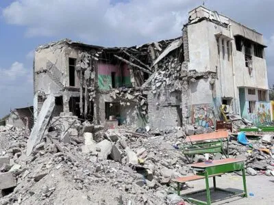 Развалины здания, возле которого стоят школьные парты.