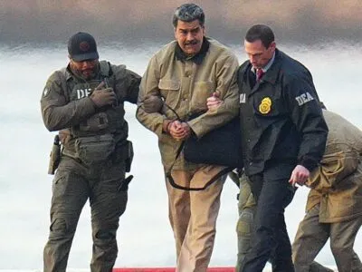 Николас Мадуро в наручниках после приземления на вертолетной площадке в Манхэттене; его сопровождают вооруженные федеральные агенты, которые ведут его к бронированному автомобилю по пути в федеральный суд Манхэттена