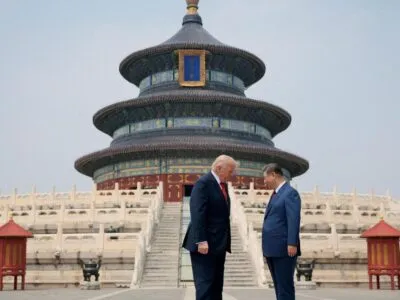 Президенты Трамп и Си Цзиньпин стоят лицом друг к другу перед богато украшенными ступенями, ведущими к величественному трехъярусному китайскому храму, выполненному в синих, зеленых, красных и золотых тонах.