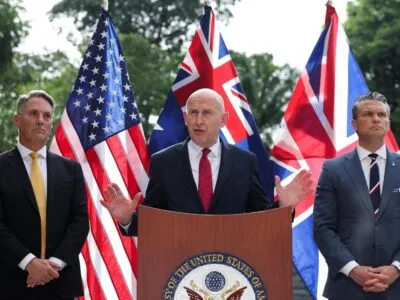 На фоне флагов Австралии, Британии и США слева направо стоят министры обороны этих стран Ричард Марлз, Джон Хили и Пит Хегсет