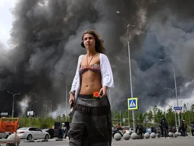 Крупнейшая за годы атака дронов на Москву. Что известно к вечеру четверга 6 Девушка с распущенными волосами, в длинной юбке и белой кофточке, накинутой на обнаженные плечи, шагает на фоне черного дыма
