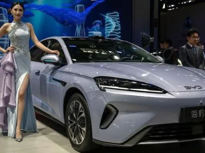 Десятки китайских компаний, включая BYD и Alibaba, попали в список Пентагона как «связанные с военными КНР» 2 Женщина в серебристом вечернем платье стоит рядом с серым электромобилем китайского автопроизводителя BYD, представленным на пресс-конференции в рамках Пекинской международной автомобильной выставки.