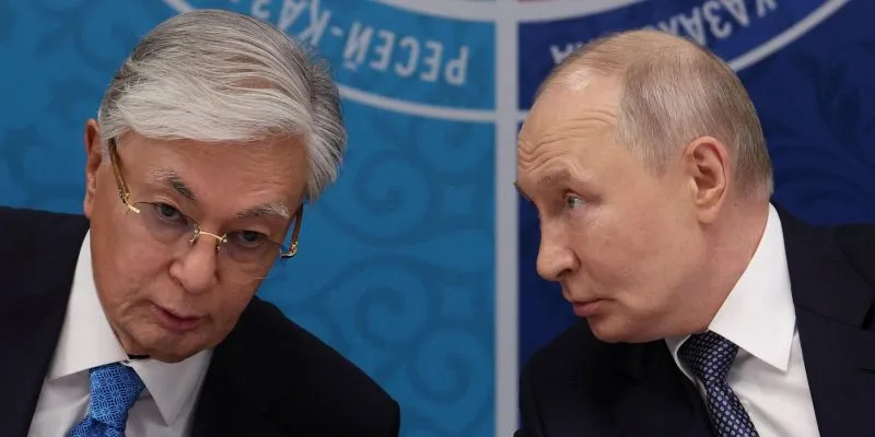Токаев и Путин за столом о чем-то говорят.
