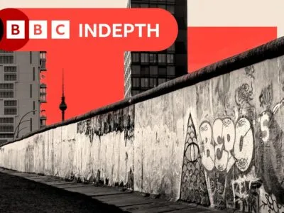 Изображение, на котором видна Берлинская стена, жилые дома по другую сторону и Берлинская телебашня на заднем плане. Фотография дополнена красным квадратом и зеленой точкой в ​​качестве элементов дизайна.
