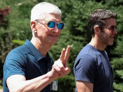 Apple подала иск против компании OpenAI и ее сотрудников, обвинив их в краже коммерческой тайны 6 Двое мужчин, один постарше и седой (Кук) показывает знак peace. На нем синее поло и солнечные очки. На мужчине помоложе синяя футболка и тоже солнечные очки. Оба не носят бороду и усы.