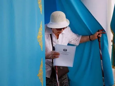 Парламентские выборы в Казахстане: партия «Адилет» набрала более 70% голосов 3 Пожилая женщина выходит из кабинки для голосования с бюллетенем в руках
