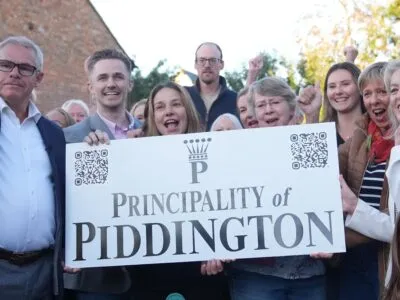 Piddington villagers stand by a sign celebrating after voting overwhelmingly to become an independent state in a symbolic “referendum”