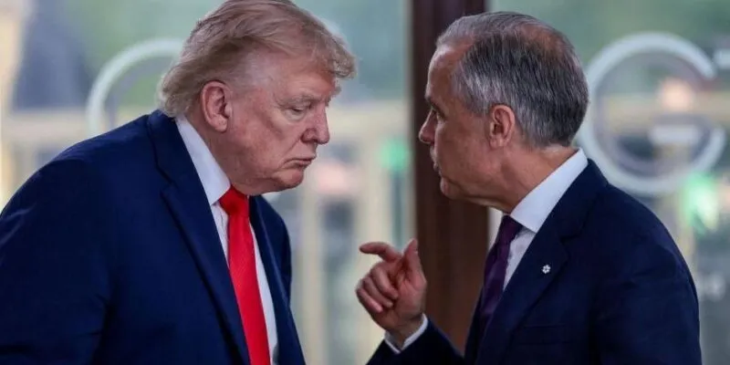 A file image showing U.S. President Donald Trump at a working lunch with Prime Minister Mark Carney and other G7 leaders. The image shows Carney and Trump side by side mid-conversation. Both are wearing a suit. Carney is gesturing with his hand mid-speech, while Trump hangs his head low to listen.