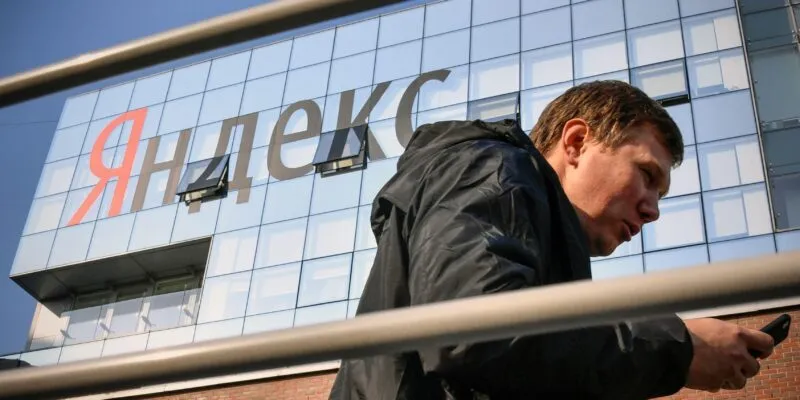 «Они большие, хорошо горят». Что происходит с дата-центрами российских компаний и почему на их защите может заработать сын генерала ФСБ 1 Мужчина со смартфоном перед зданием с вывеской «Яндекс»