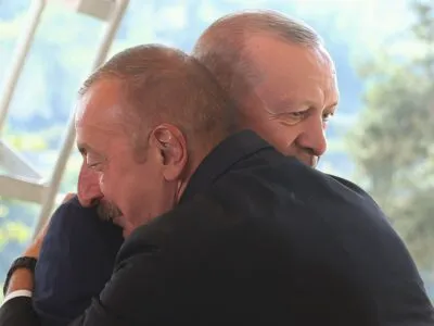 Алиев: «Нам никто не помог». Может ли Израиль разлучить Баку и Анкару? 3 Двое улыбающихся мужчин крепко обнимают друг друга - один из них Ильхам Алиев в темном костюме с усами, прижался щекой к плечу другого, президента Турции Эрдогана, тоже в темном костюме, который смотрит вниз