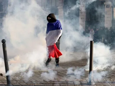 A protester wrapped in a French flag stands with smoke all around on a street in Lille on 17 October.